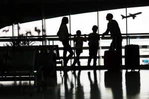 Silhouette of family with two children at the airport in front of airplane.